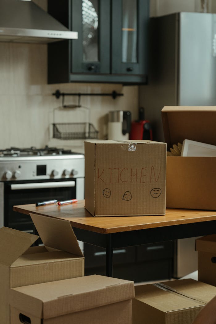 Cardboard moving boxes in a modern kitchen, ready for relocation.