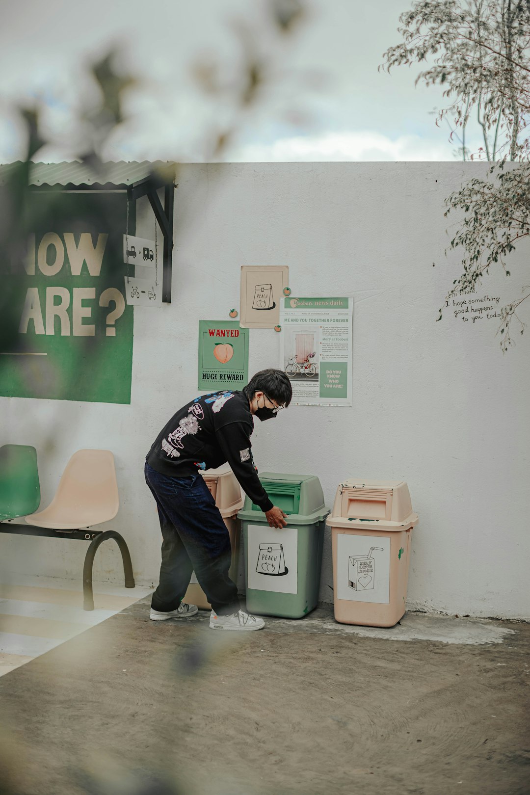 a-man-standing-next-to-a-green-trash-can-bqrttnmpa0c